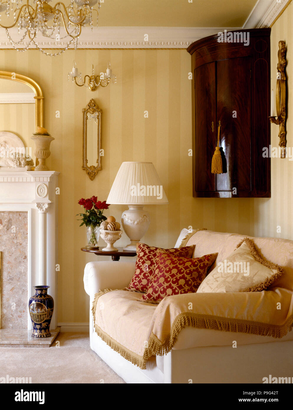 Antica angoliera e divani color crema con frange attraverso in salotto con  carta da parati a strisce Foto stock - Alamy