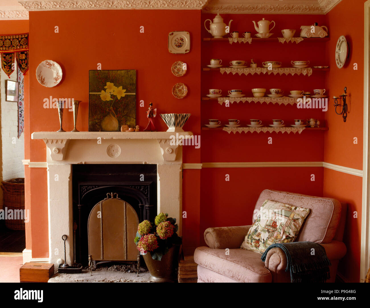 Collezione di vintage Cina sull'alcova scaffale accanto a un caminetto bianco in un arancione la stanza di seduta Foto Stock