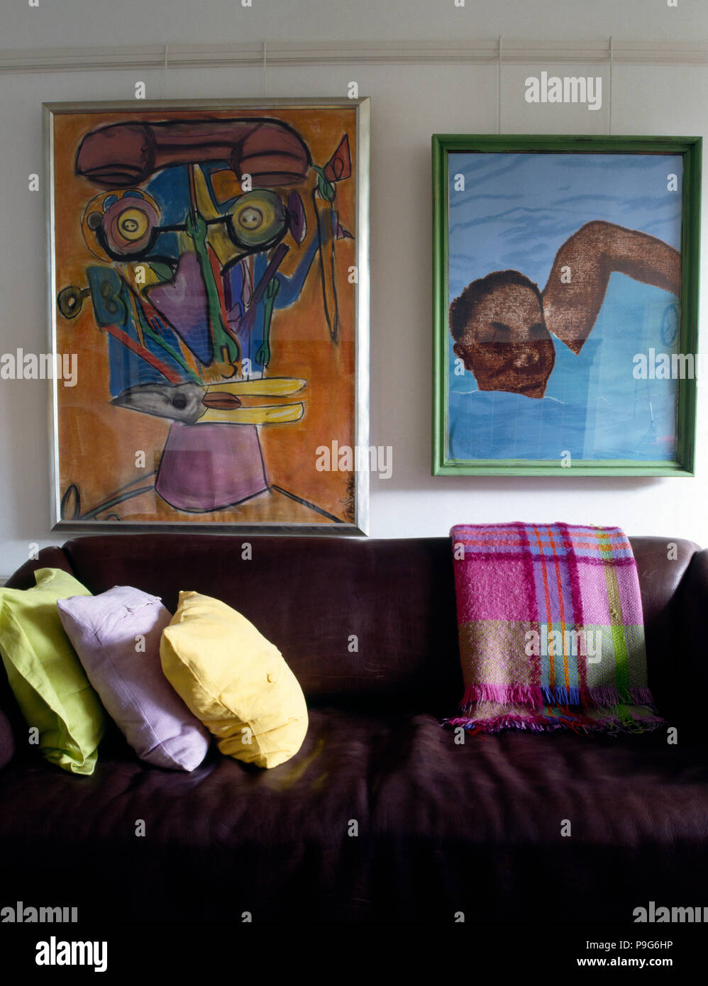 Anni Novanta soggiorno con immagini sulla parete sopra divano marrone con colorata lana buttare e cuscini color pastello Foto Stock