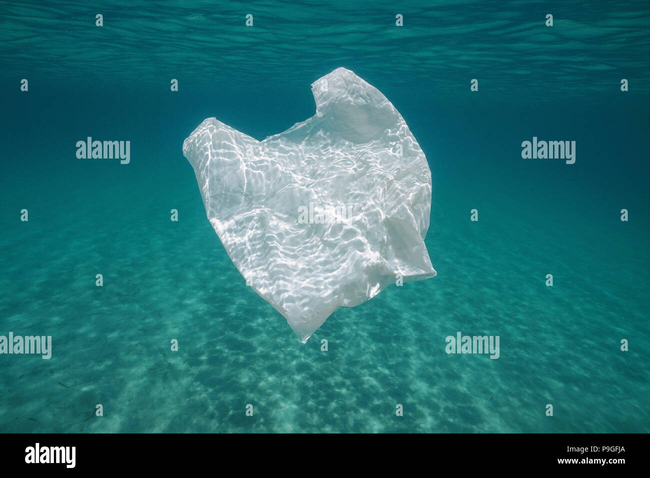 Inquinamento subacquea in una borsa di plastica in mare tra la superficie dell'acqua e un fondale sabbioso, Mediterraneo Almeria, Andalusia, Spagna Foto Stock