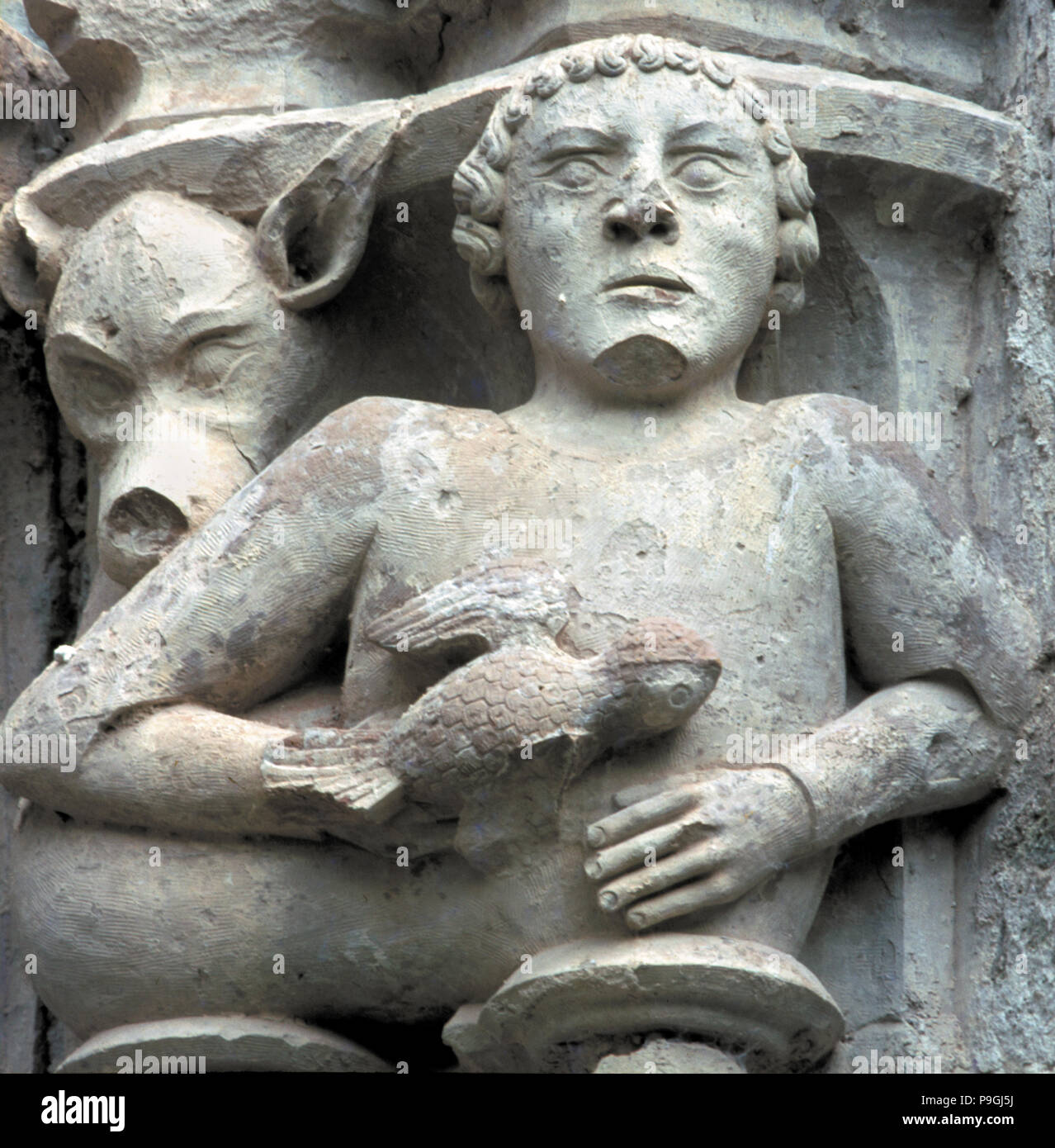 Dettaglio di un capitale che mostra un uomo con un piccione in mano, nel chiostro del monastero di … Foto Stock
