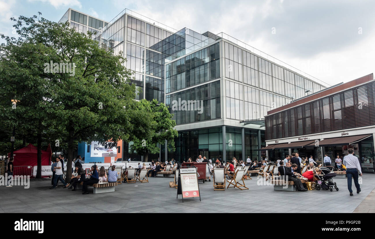 Persone relax sulle sdraio o panche di legno in chat con i Vescovi Square, una proprietà privata di spazio pubblico in Spitalfields London. Patisserie Valerie Foto Stock