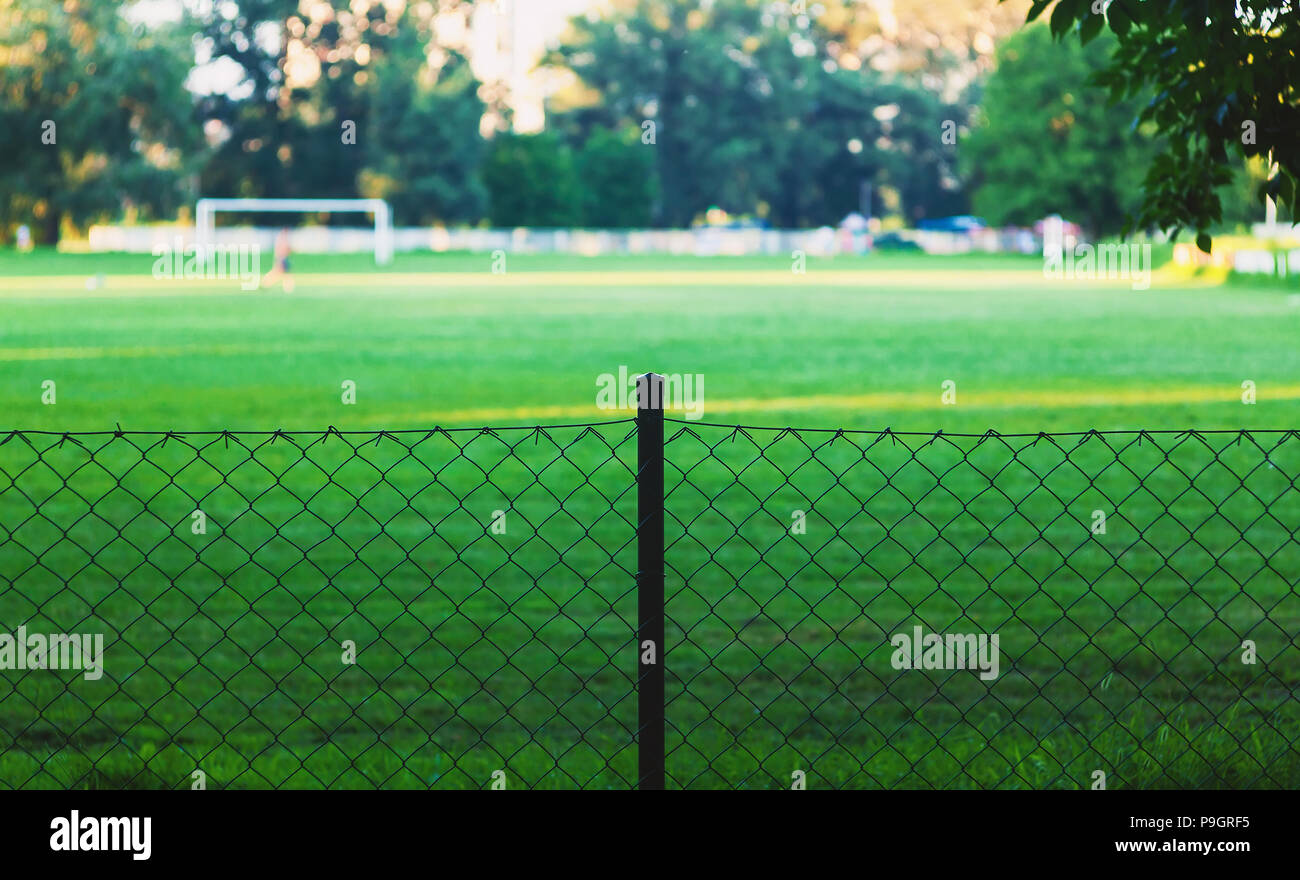 Parco giochi di calcio in sfondo sfocato, focus sulla recinzione metallica. Foto Stock