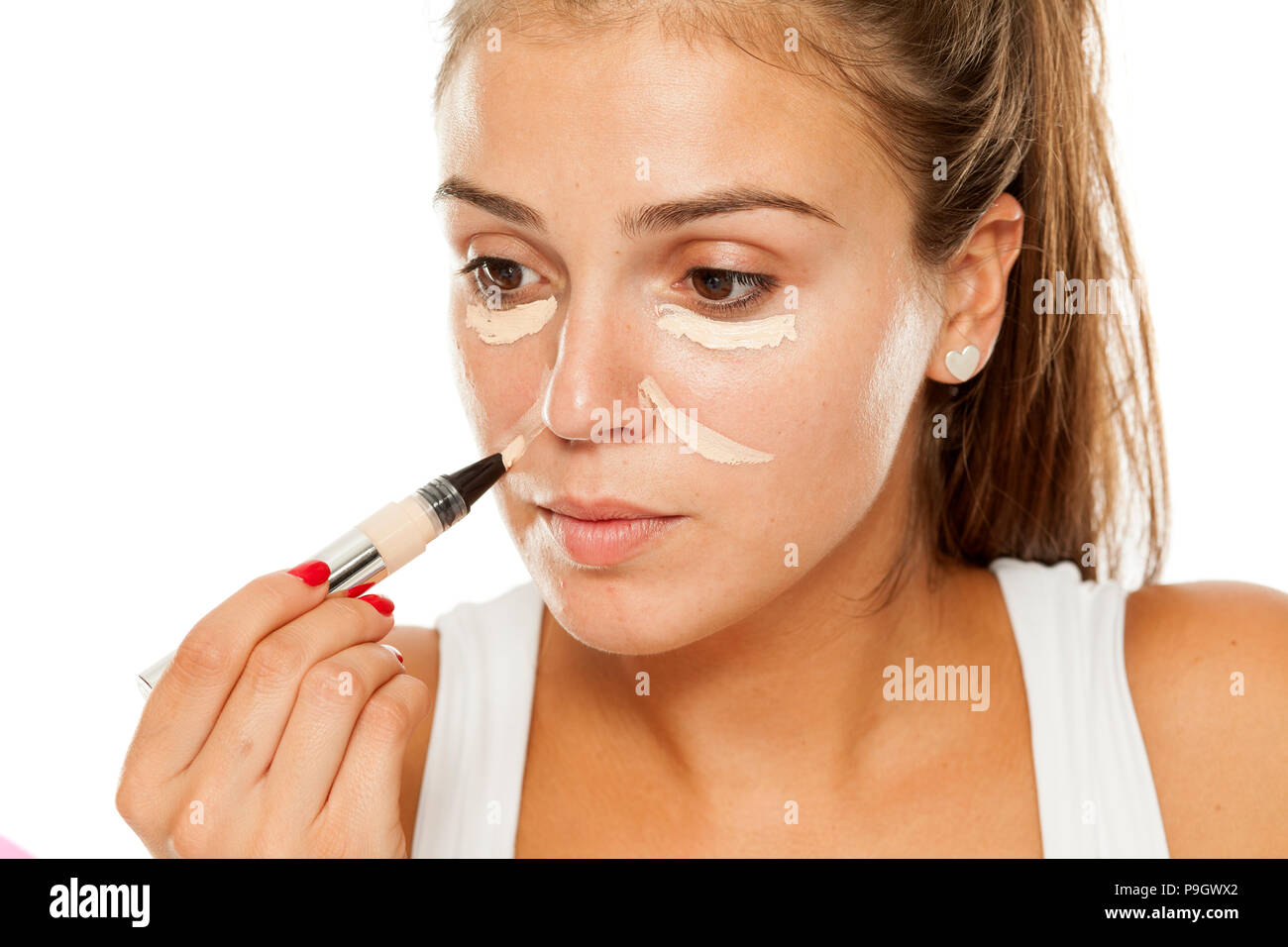 Giovani donne applicati correttore sotto gli occhi ed il naso con applicatore Foto Stock