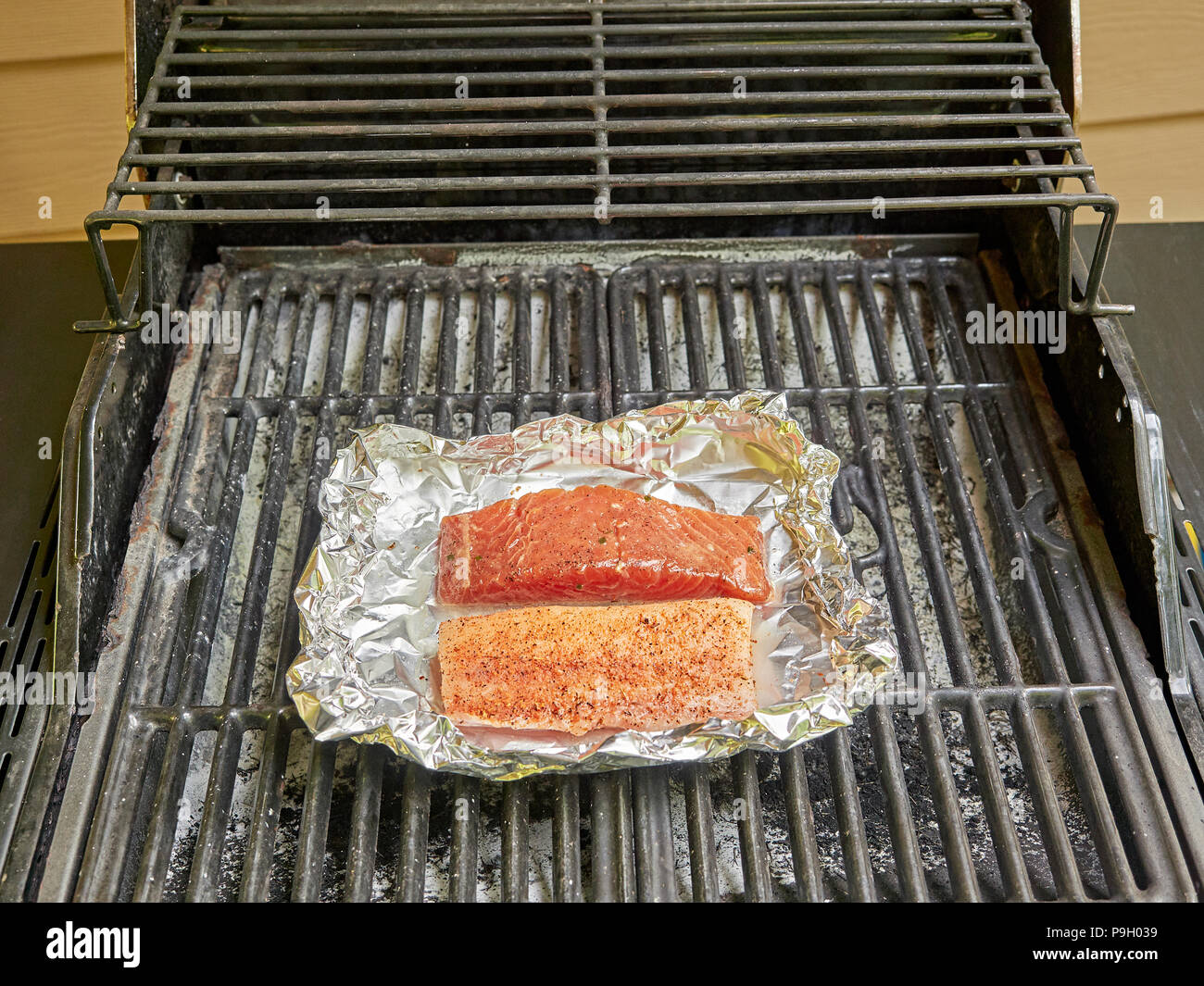 La cottura di salmone e bianco i filetti di pesce su un grill all'aperto utilizzando la stagionatura. Foto Stock