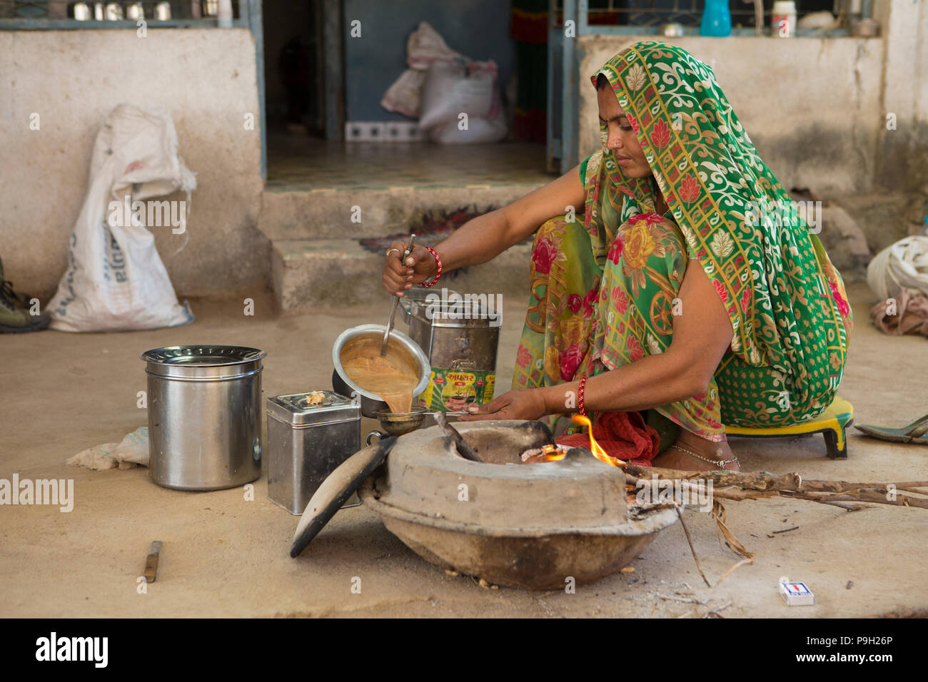 Una donna che fa Indian chai su un fuoco di legno aperto presso il loro domicilio in Ahmedabad, India. Foto Stock