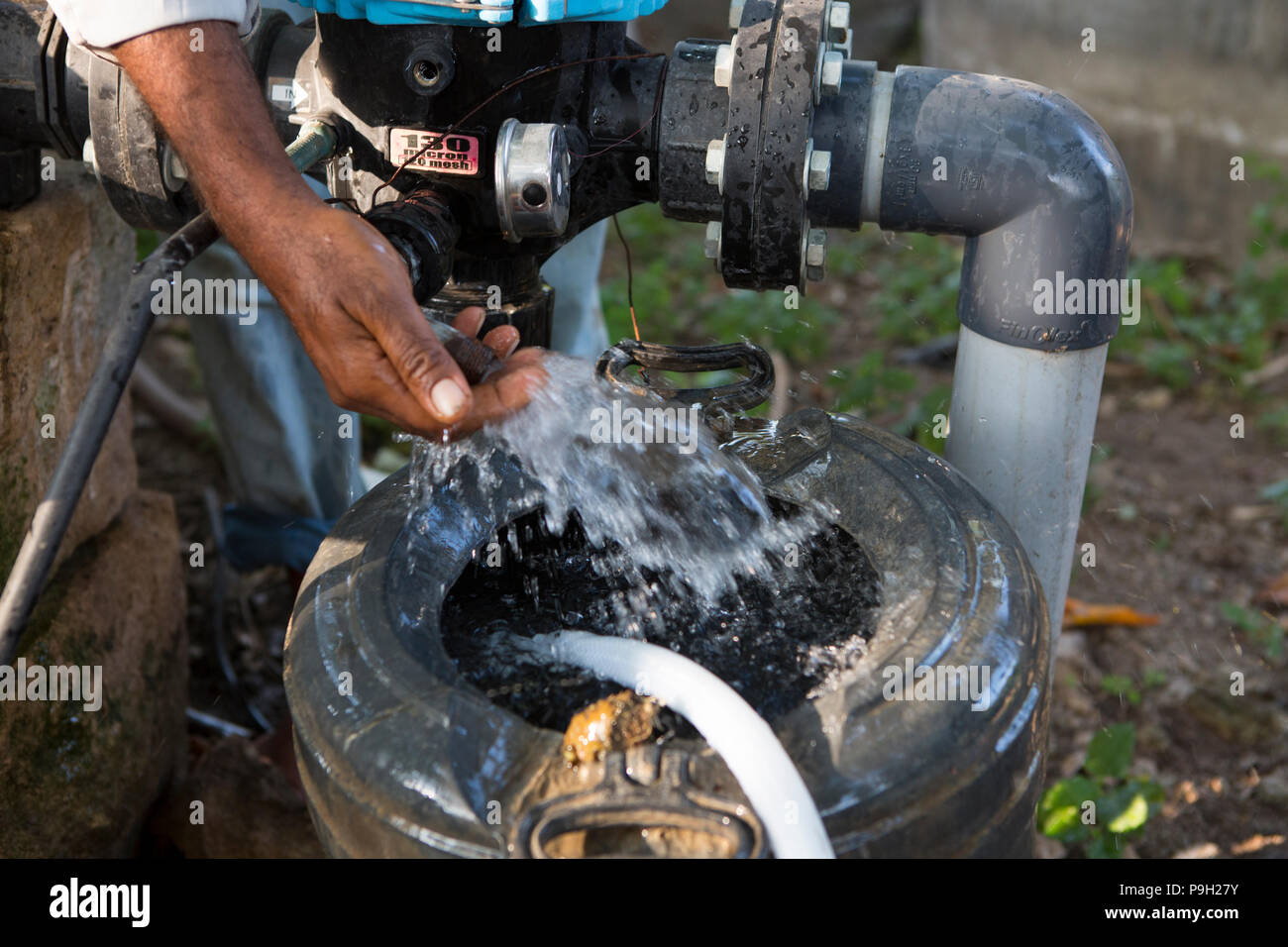 Un agricoltore si accende la sua pompa dell'acqua per la sua irrigazione a goccia. Foto Stock