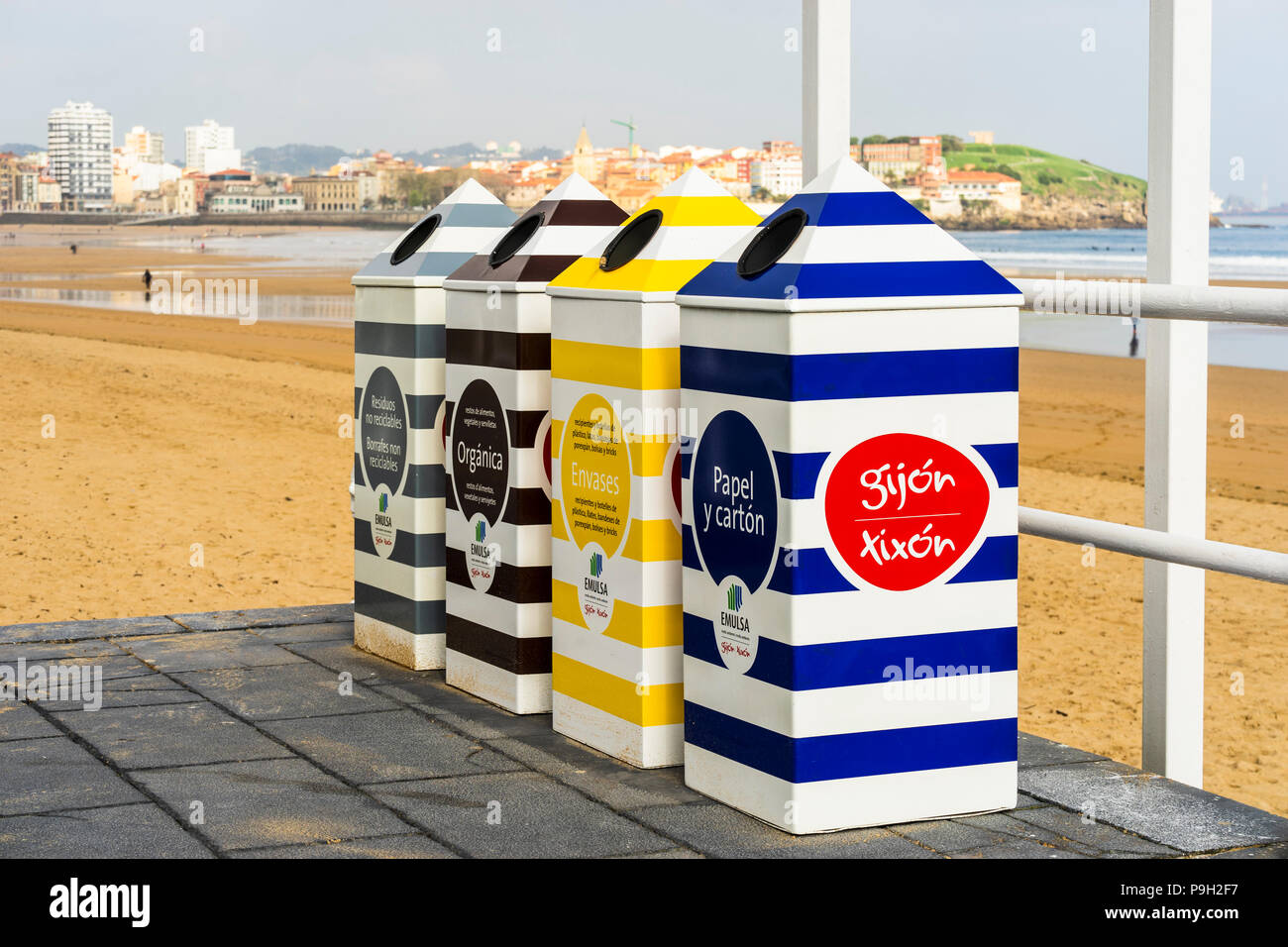 Quattro contenitori colorati per il riciclaggio da spiaggia in Gijon, Asturias, Spagna Foto Stock