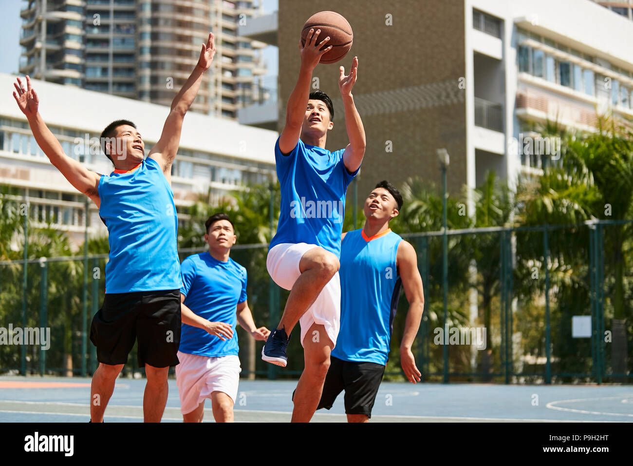 Giovani asiatici giocatori adulti giocare a basket sul tribunale aperto. Foto Stock