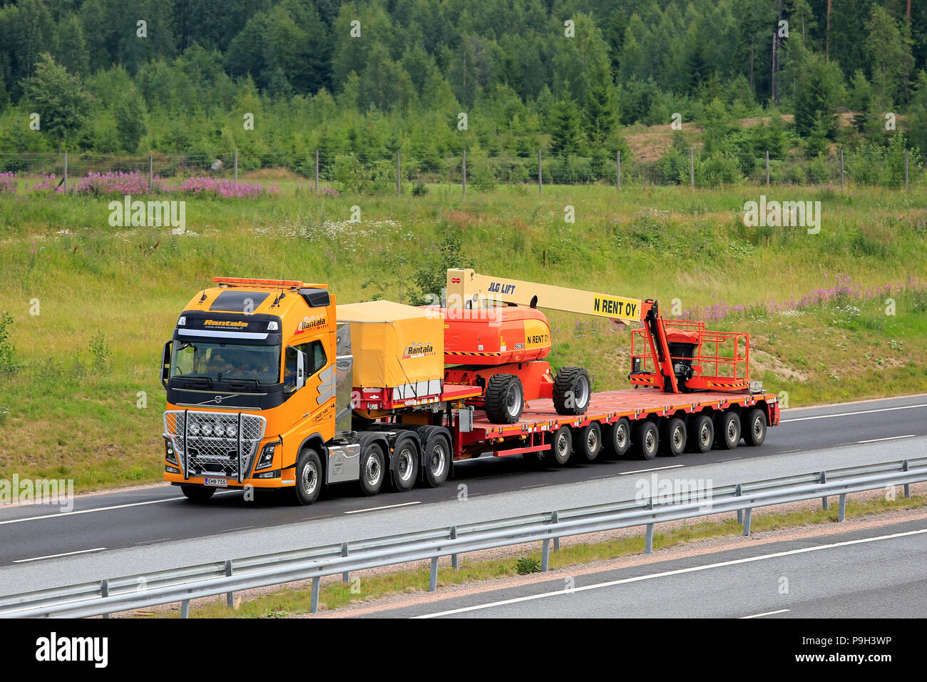 Giallo Volvo FH semi rimorchio di trasporto Rantala JLG 860SJ telescopici di sollevamento del braccio su rimorchio lungo l autostrada in estate. Salo, Finlandia - 13 luglio 2018. Foto Stock