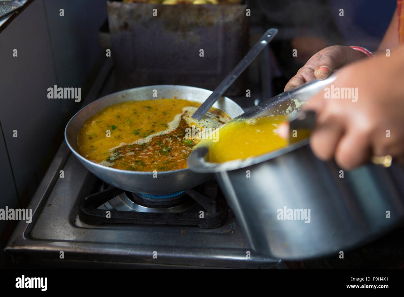Una donna che fa il curry il pranzo nella loro cucina a casa. Foto Stock