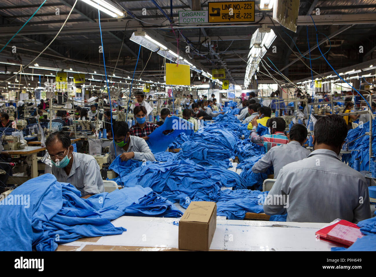 Una vista in basso la lunghezza di una linea di produzione in una fabbrica di abbigliamento a Indore, India. Foto Stock