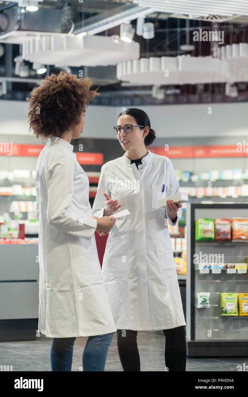 Due colleghi amichevole conversazione mentre lavorano insieme come farmacisti Foto Stock