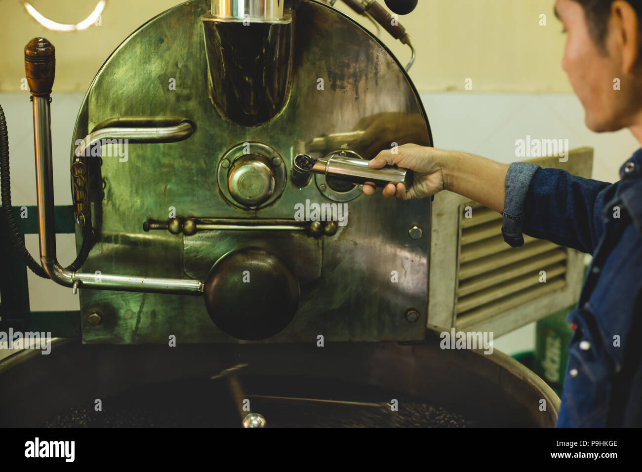 Mano del tostatore tenendo una sonda di fresco il caffè torrefatto in grani Foto Stock
