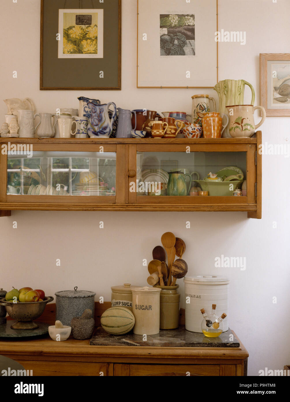 Raccolta di caraffe vintage sulle strette, vetro parete frontale ripiani in un vecchio cucina Foto Stock