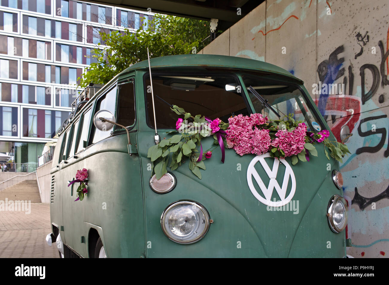 Bremen, Germania - Luglio 17th, 2018 - Verde VW T3 van con grandi bianchi logo VW con una moderna facciata in vetro e in background Foto Stock