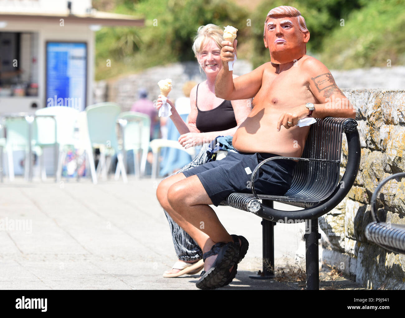 Uomo in Donald Trump maschera godendo il sole in Plymouth,Devon, Regno Unito Foto Stock