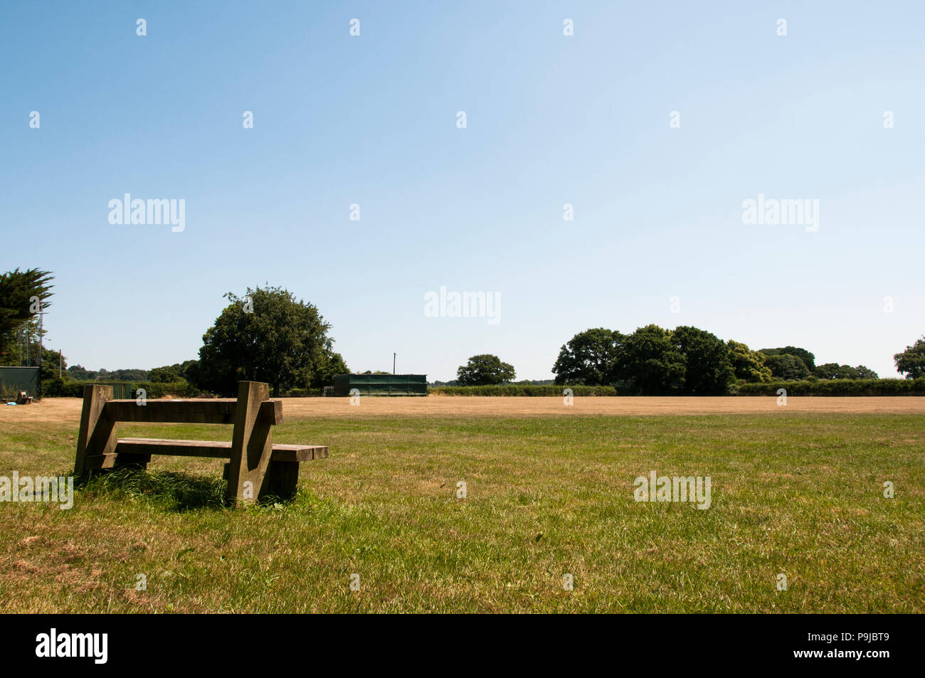 Un unico banco cercando su un campo vuoto. Un buon posto per sedersi e pensare Foto Stock