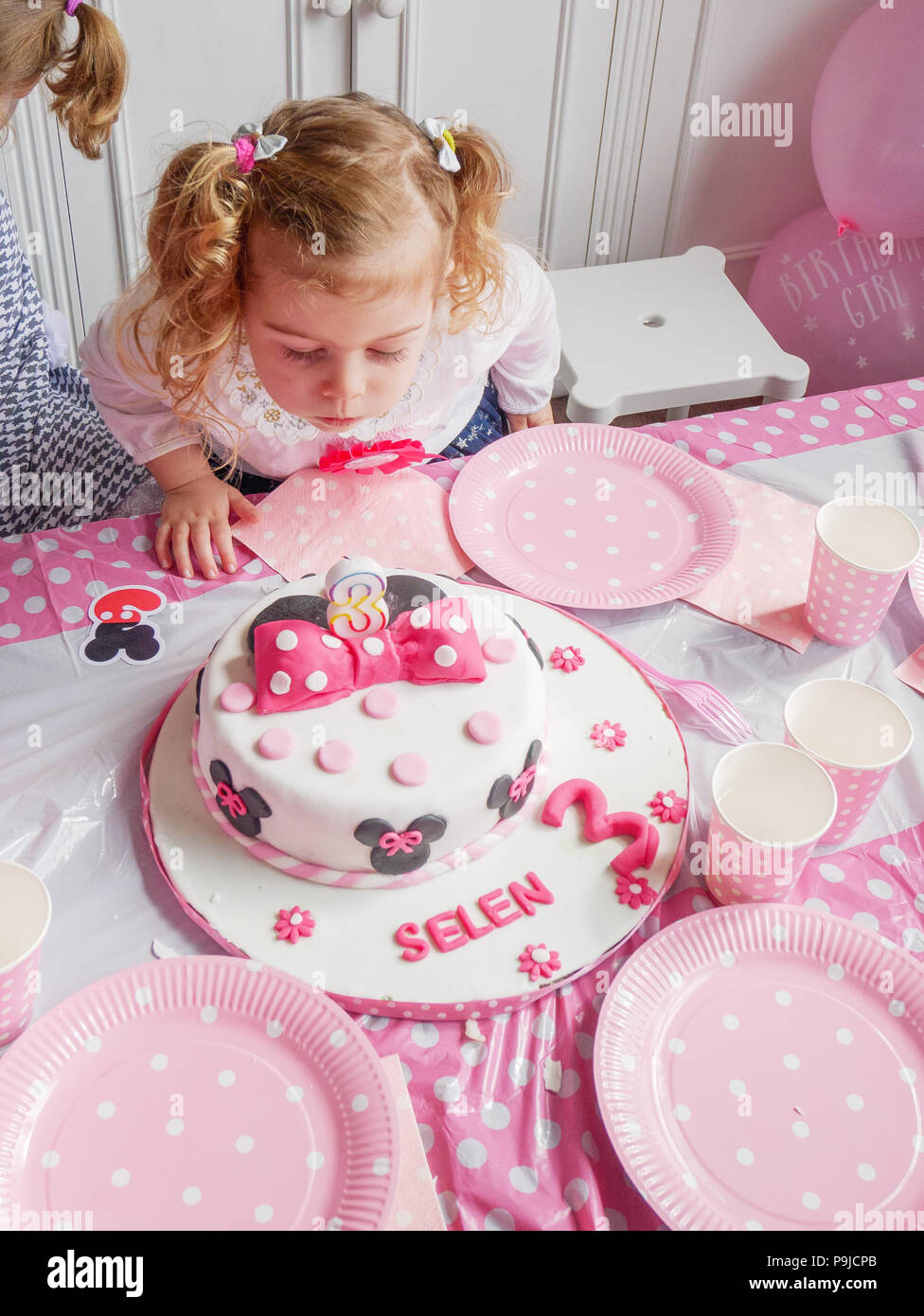 Bimba di tre anni soffiando le candeline sulla sua torta di compleanno,  REGNO UNITO Foto stock - Alamy