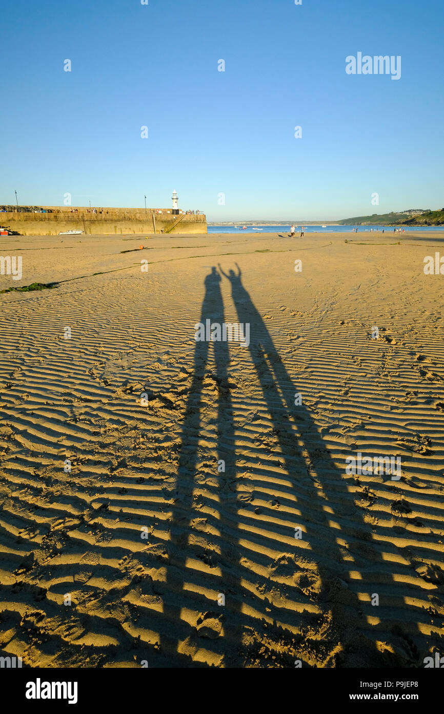 Ombre lunghe di due persone sulla spiaggia la sera sun a St Ives in Cornovaglia Foto Stock