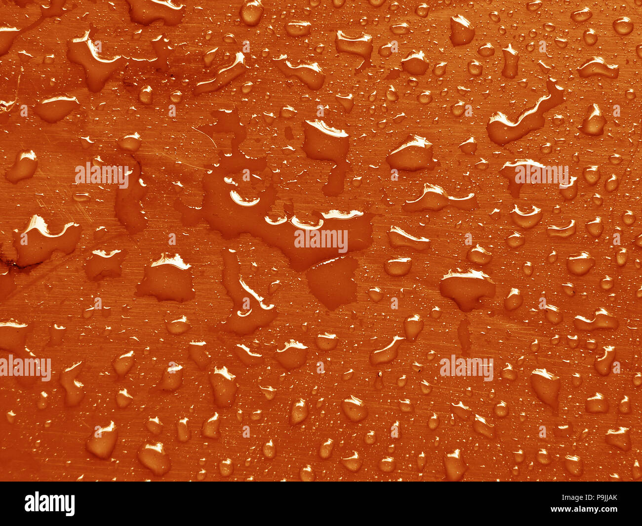 Gocce d'acqua sulla russet color arancio superficie metallica Foto Stock