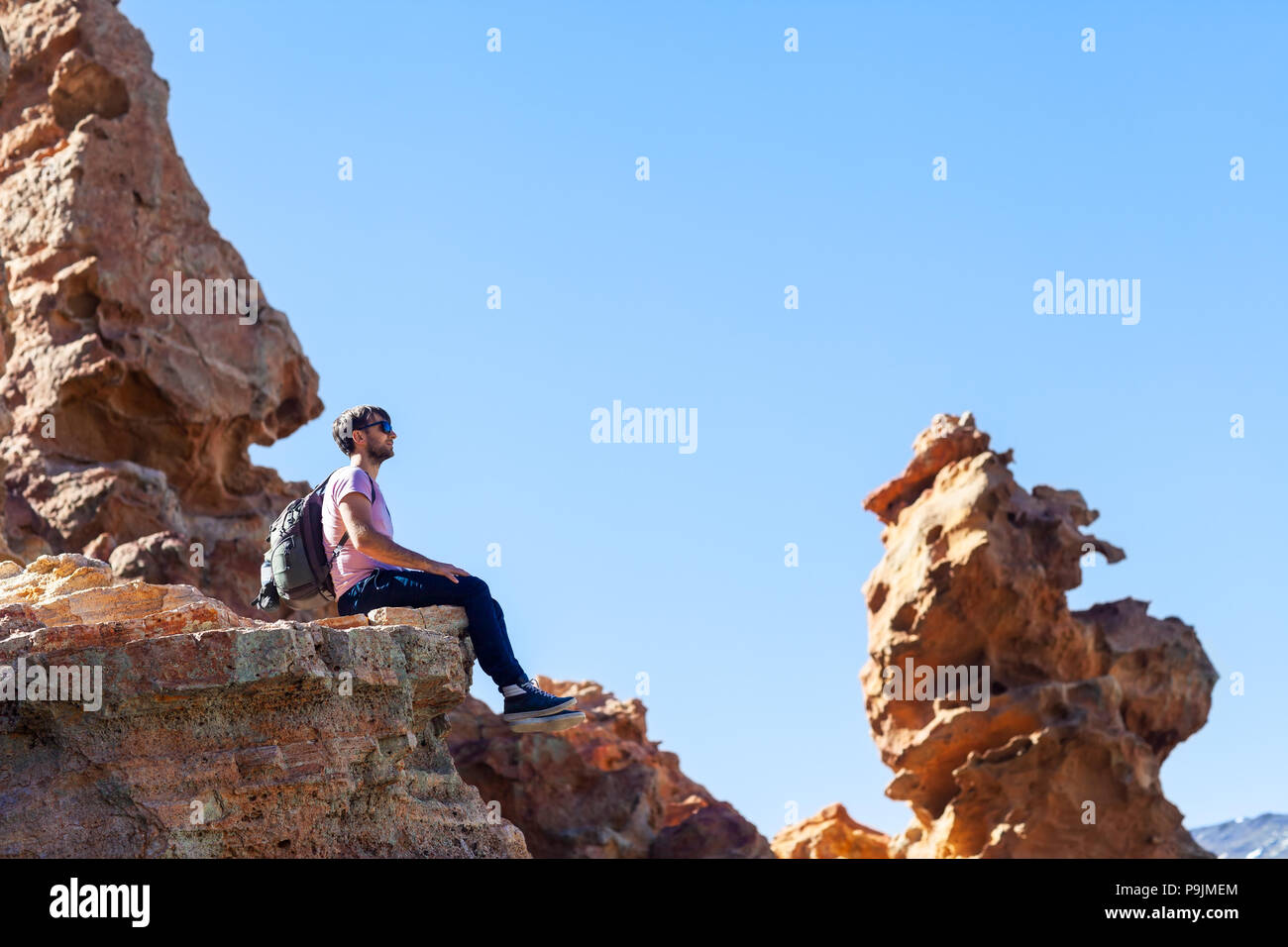 Traveler uomo seduto sulla montagna nel canyon. Parco nazionale di Tenerife, Isole Canarie, Spagna Foto Stock