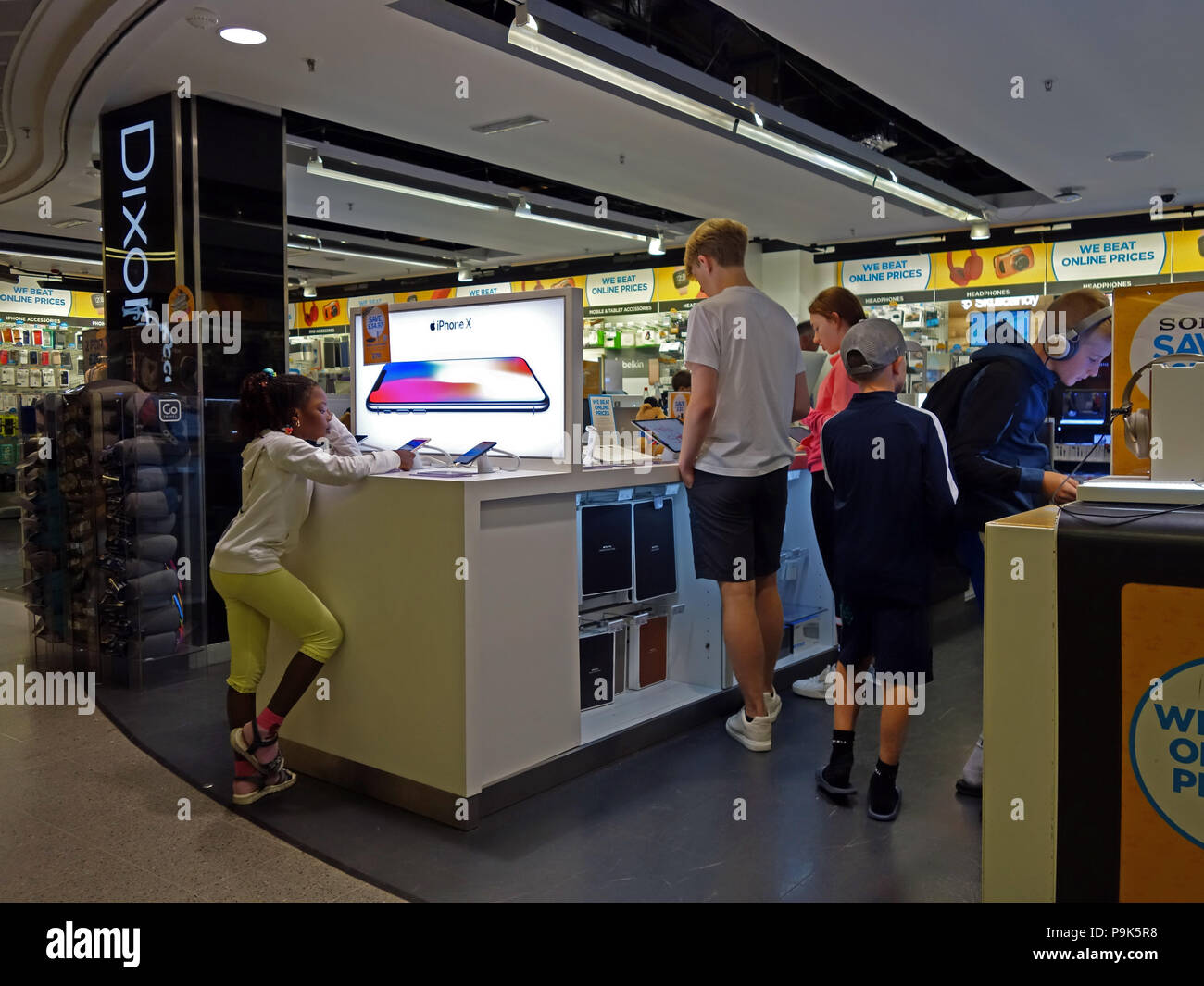 Giovani guardando le apparecchiature elettroniche in vendita nei duty free Lounge sezione elettronica all'Aeroporto di Manchester. Foto Stock