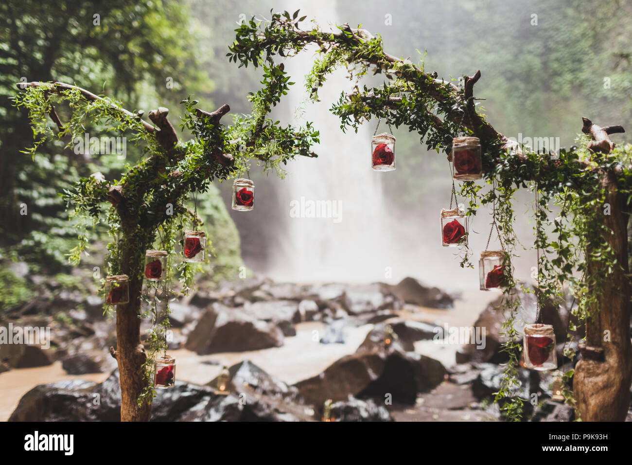 Tropical cerimonia di nozze con cascata vista nella giungla canyon. Decorate con verde edera, antiche filiali e lampade pensili Foto Stock