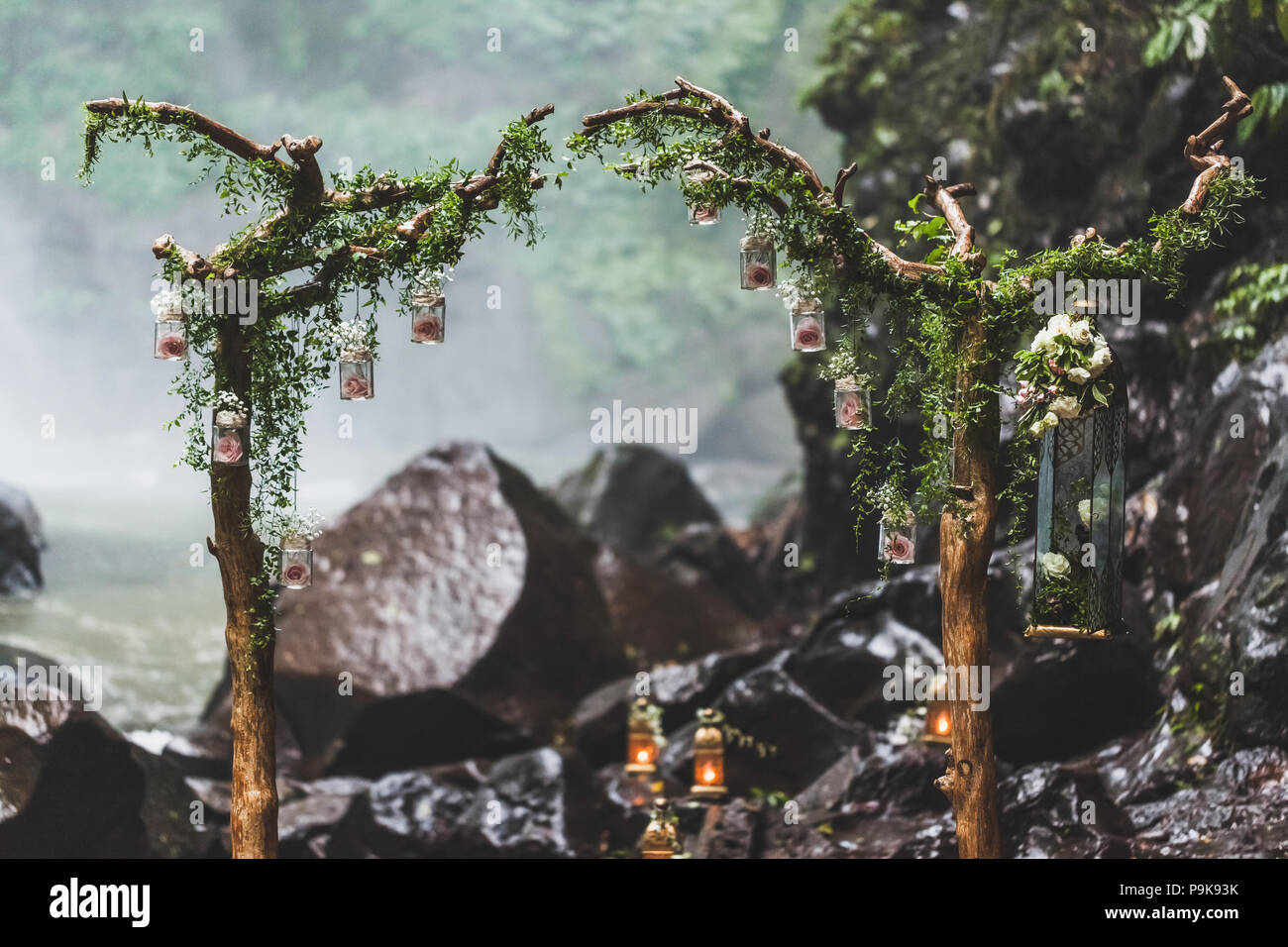 Tropical cerimonia di nozze con cascata vista nella giungla canyon. Decorate con verde edera, antiche filiali e lampade pensili Foto Stock
