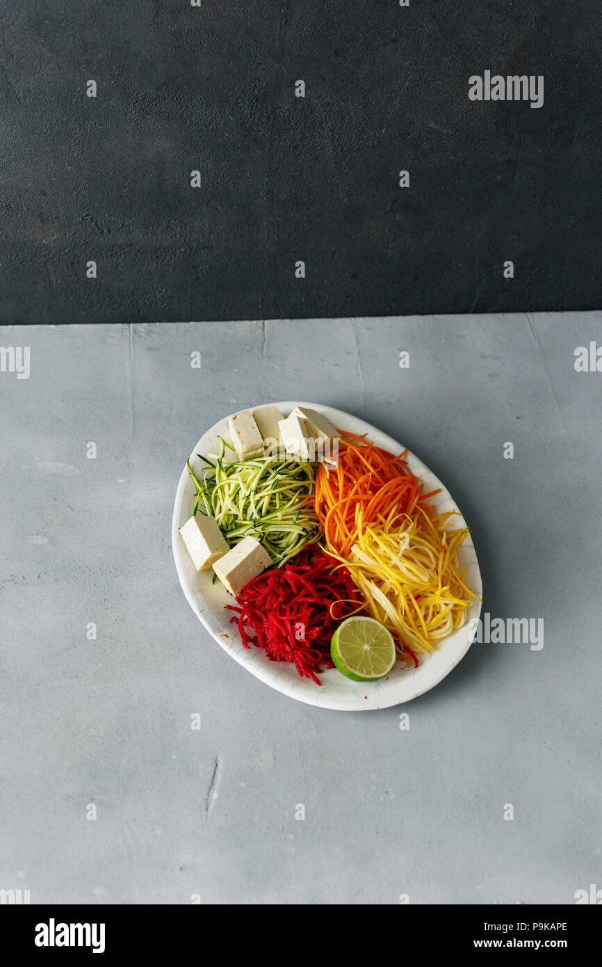 Pulire sani spiralizzato verdure con formaggio di tofu in calcestruzzo di colore grigio nella tabella Foto Stock