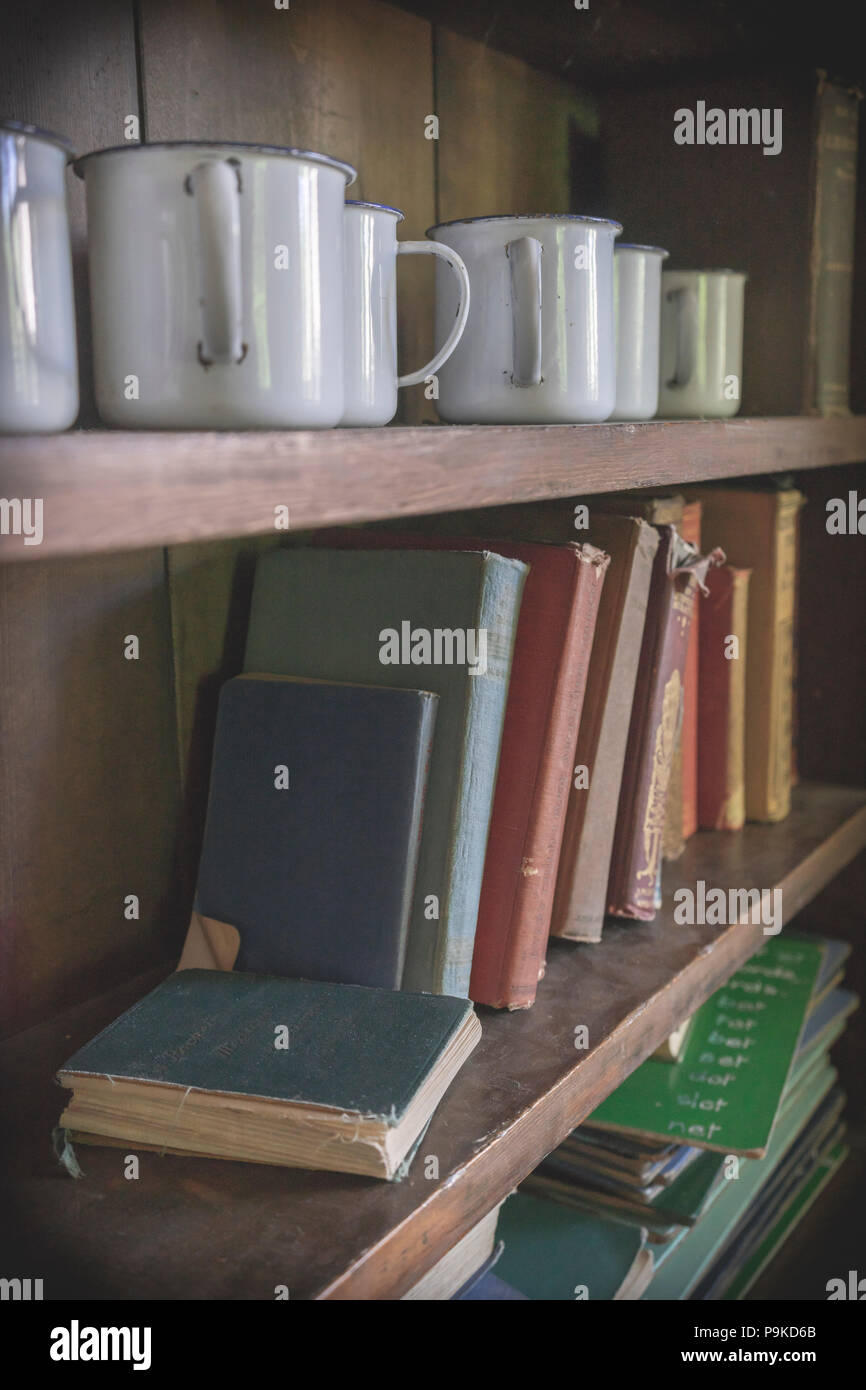 Interno della scuola Tyneham (oggi utilizzato come una fiera), mensole con libri vecchi e tazze in abbandonato Tyneham village, Dorset, England, Regno Unito Foto Stock