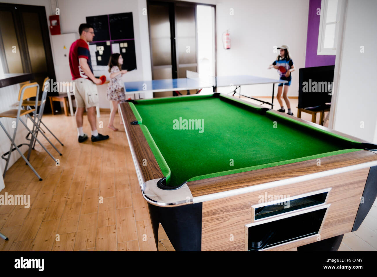 Una sala giochi con tavolo da biliardo nella parte anteriore di una  famiglia - il padre è giocando a ping-pong con le sue figlie nel luminoso  bar e il centro per il