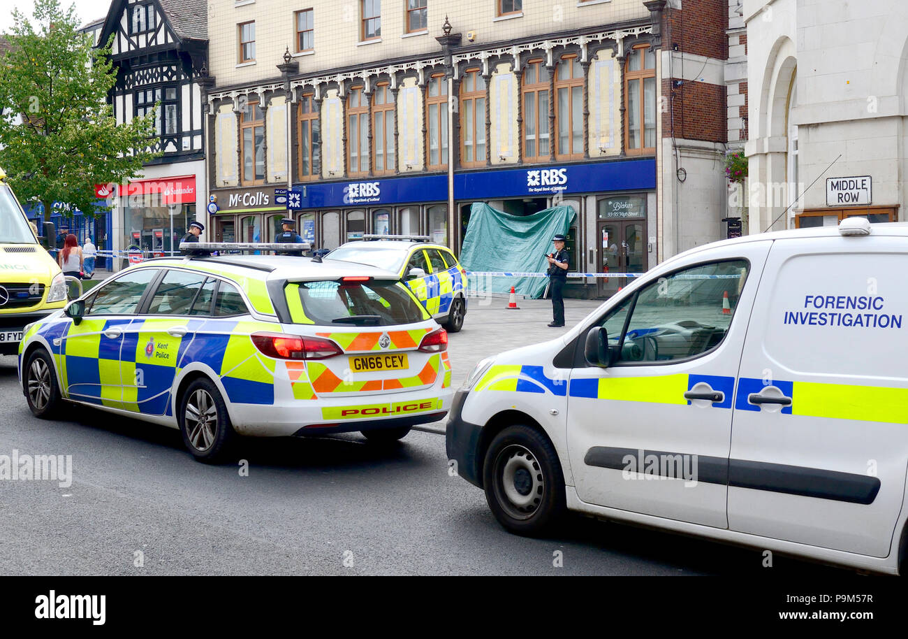 Maidstone, Kent, Regno Unito. 19 Luglio, 2018. Diversi auto della polizia, ambulanza e analisi forense team circondano la Royal Bank of Scotland succursale in Maidstone High Street a seguito della morte di una traversina ruvida. Una grande area del Giubileo piazza nel centro della città è stato isolato dopo la scoperta del corpo nel vano della porta del ramo RBS questa mattina. Le forze di polizia sono stati chiamati intorno alle 8:45am - La morte non viene trattata come sospetta. Credito: PjrNews/Alamy Live News Foto Stock