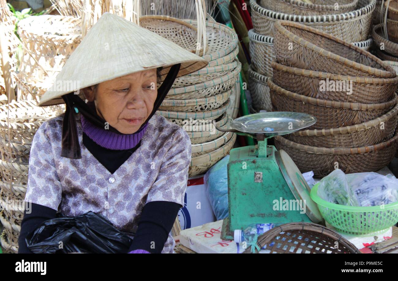 Una donna vendita di ceste in una fase di stallo in un mercato in Vietnam Foto Stock