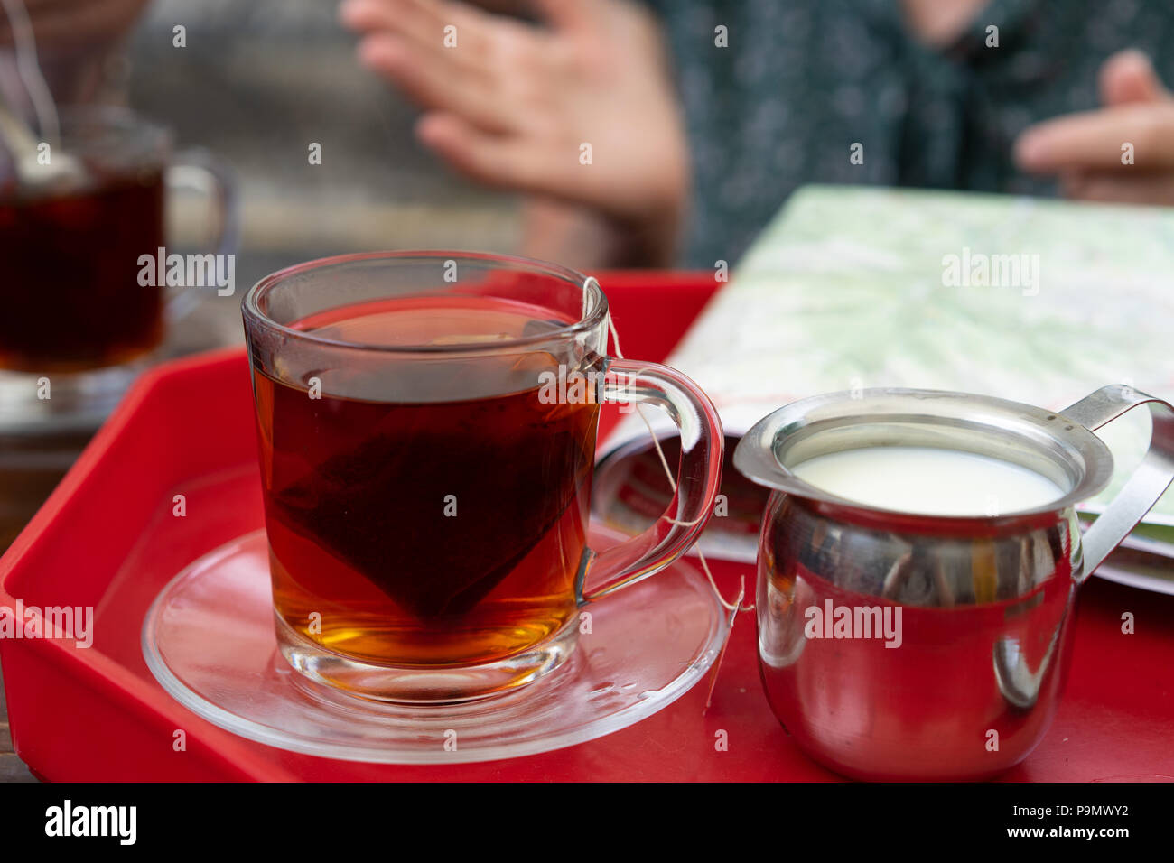 Il tè in un bicchiere di vetro con un contenitore di latte, Polonia. Foto Stock