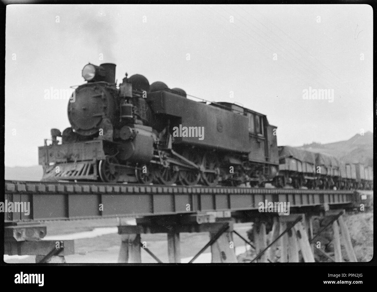 303 locomotiva a vapore alaggio vagoni merci, attraversando un non ben identificato il ponte ferroviario ATLIB 340079 Foto Stock