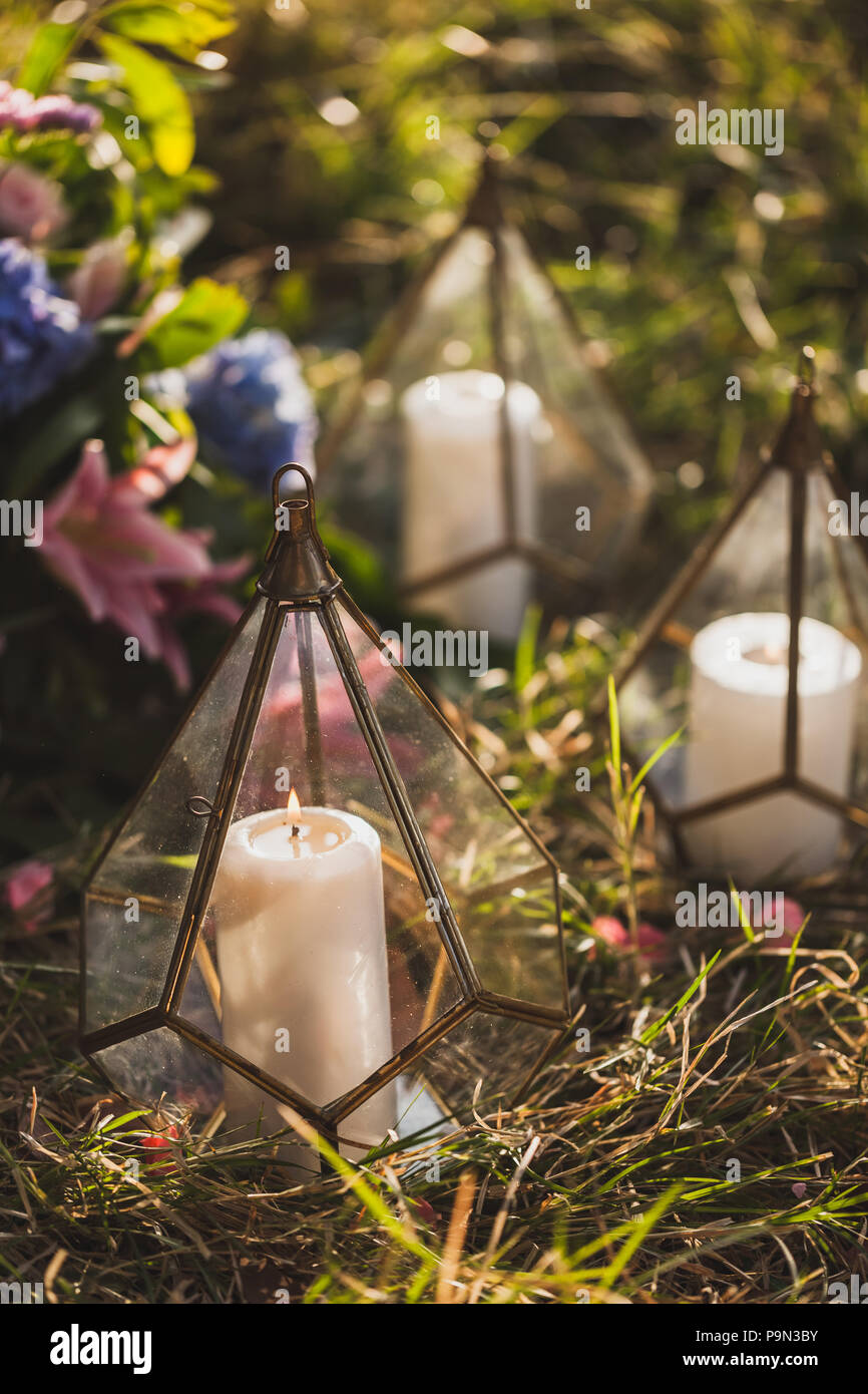 Cerimonia di matrimonio decorazione con un sacco di candele all'interno di  vetro trasparente cono fatti a mano le caselle. Petali di fiori intorno in  erba Foto stock - Alamy