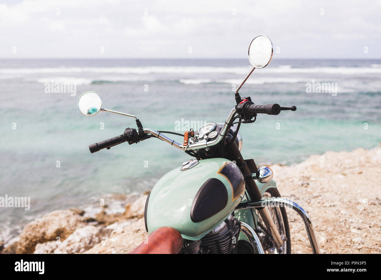 Vecchia motocicletta vintage in piedi sul bordo della scogliera con incredibile vista oceano Foto Stock