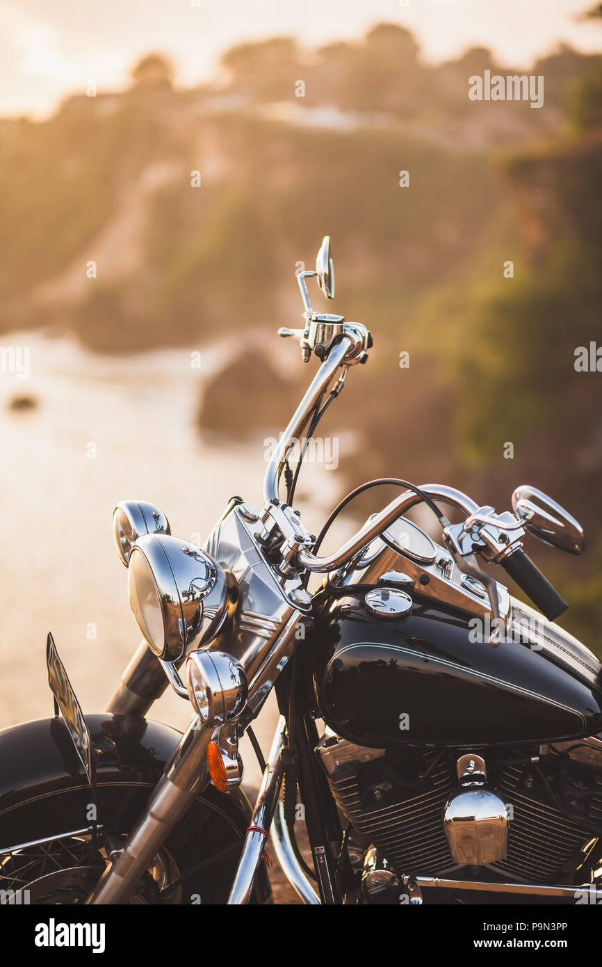 Vecchia motocicletta vintage in piedi sul bordo della scogliera a luce calda del sole all'alba, lucido dettagli del bike close-up Foto Stock