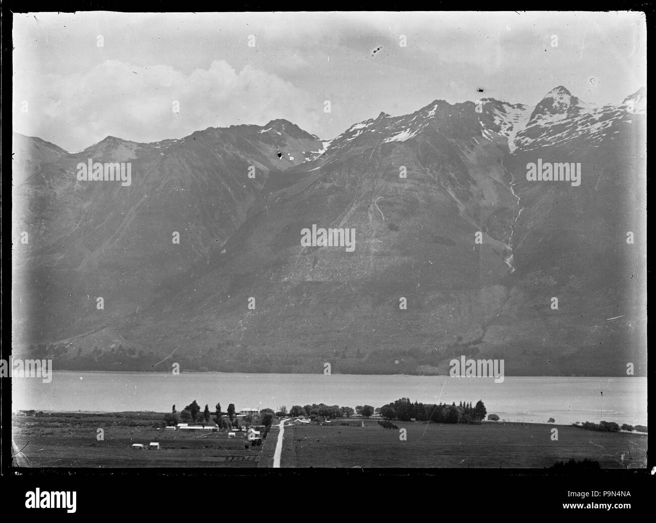 323 vista di una fattoria non identificato sulle rive di un lago, con una gamma di montagna sul lato lontano dall'acqua. ATLIB 294483 Foto Stock