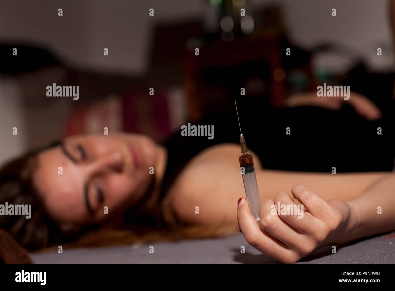 Un drogato ragazza distesa sul pavimento con una siringa in mano Foto Stock