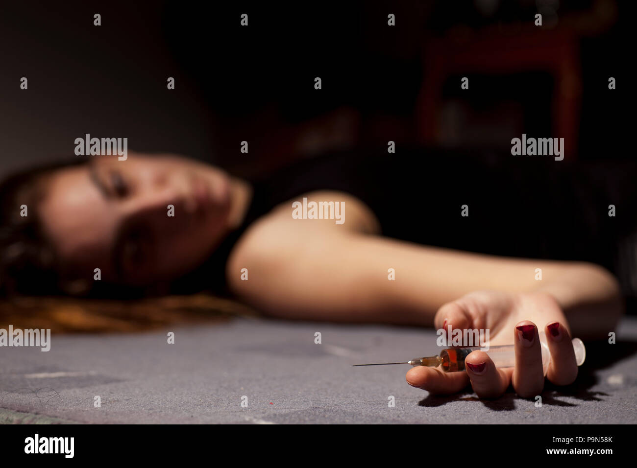 Un drogato ragazza distesa sul pavimento con una siringa in mano Foto Stock
