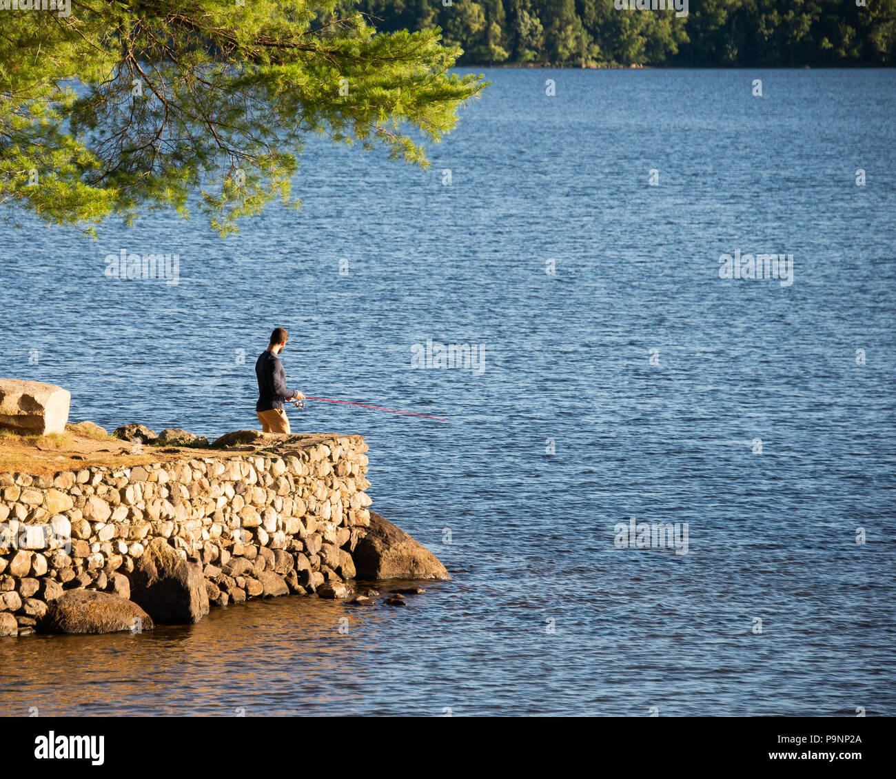 Un uomo pesca su Osborne punto sul Lago Pleasant presso il villaggio Parco in speculatore, NY USA nel Parco Adirondack. Foto Stock