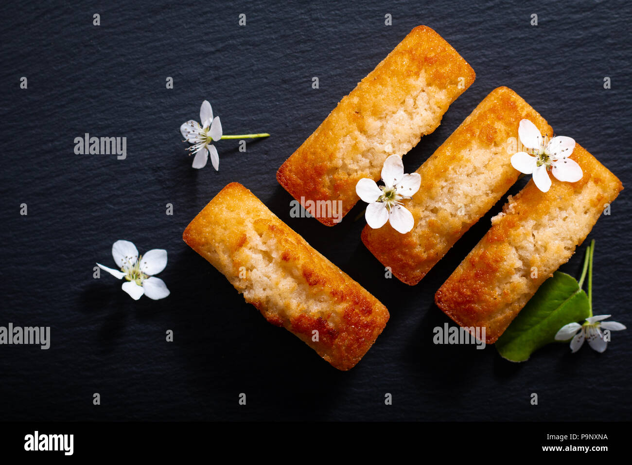 Concetto di cibo francese mini torta di mandorle finanziere su ardesia nera pietra con spazio di copia Foto Stock