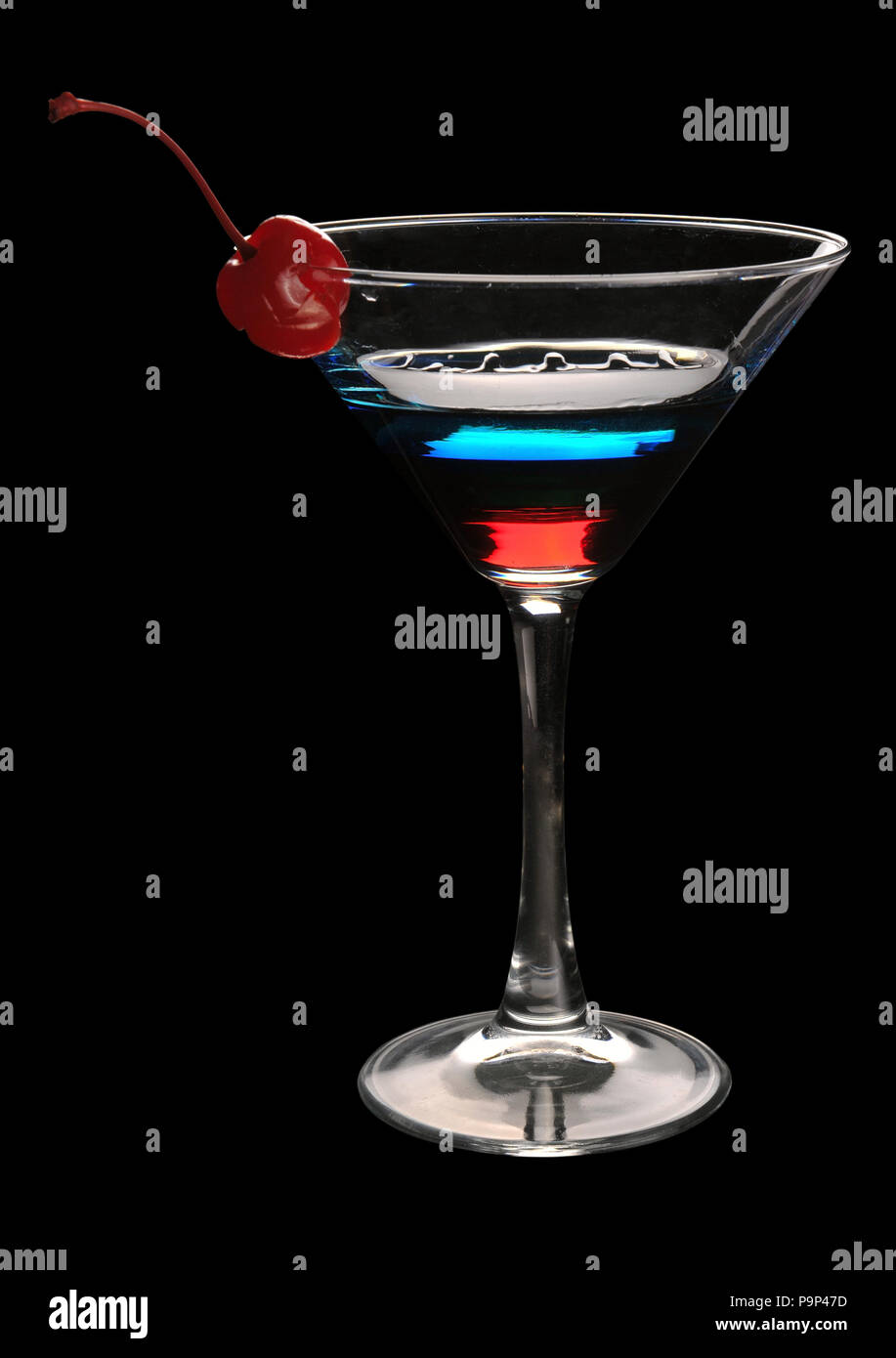 Tri-colore martini cocktail con una ciliegia su uno sfondo nero Foto Stock
