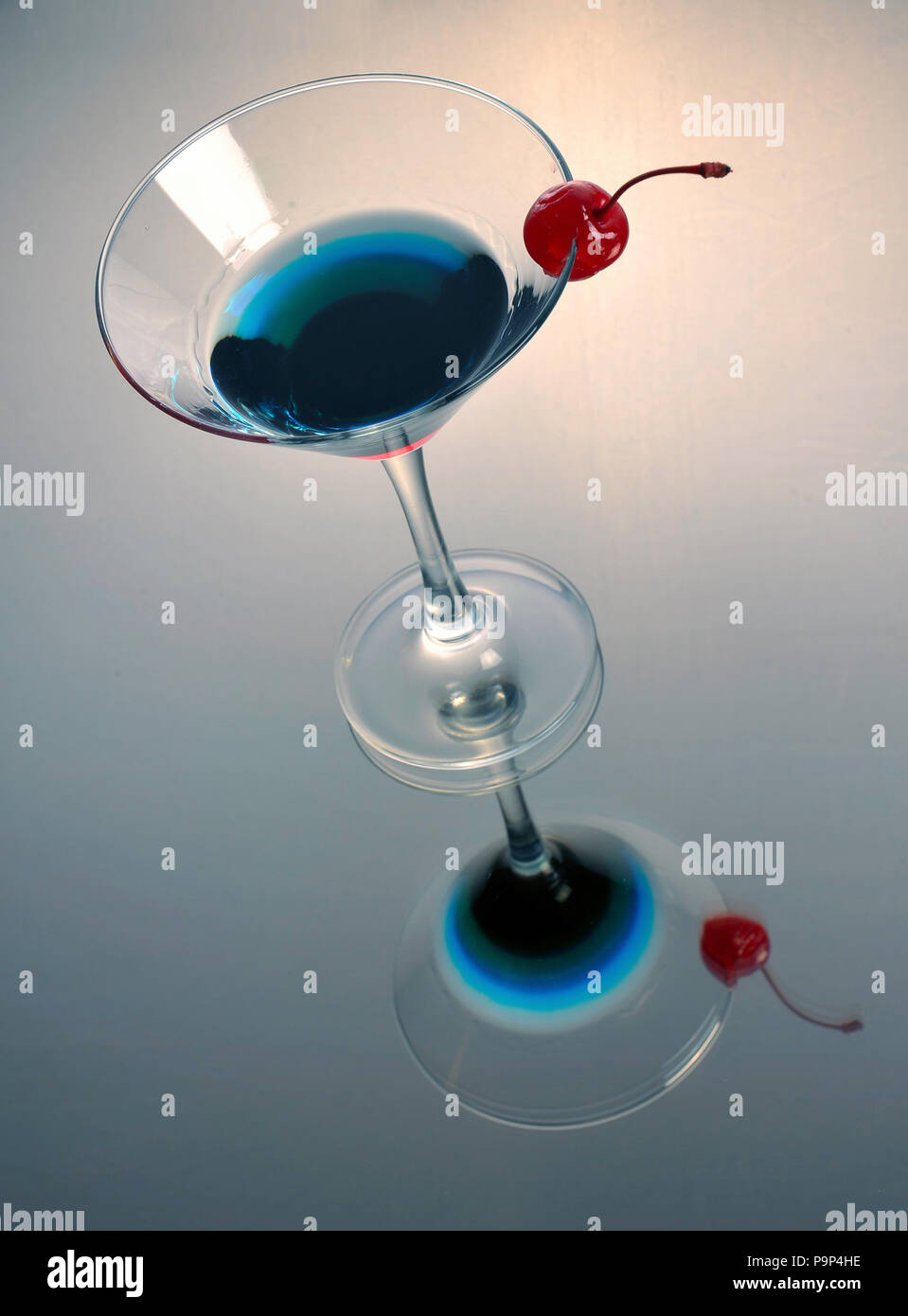 Tri-colore martini cocktail con una ciliegia e la riflessione Foto Stock