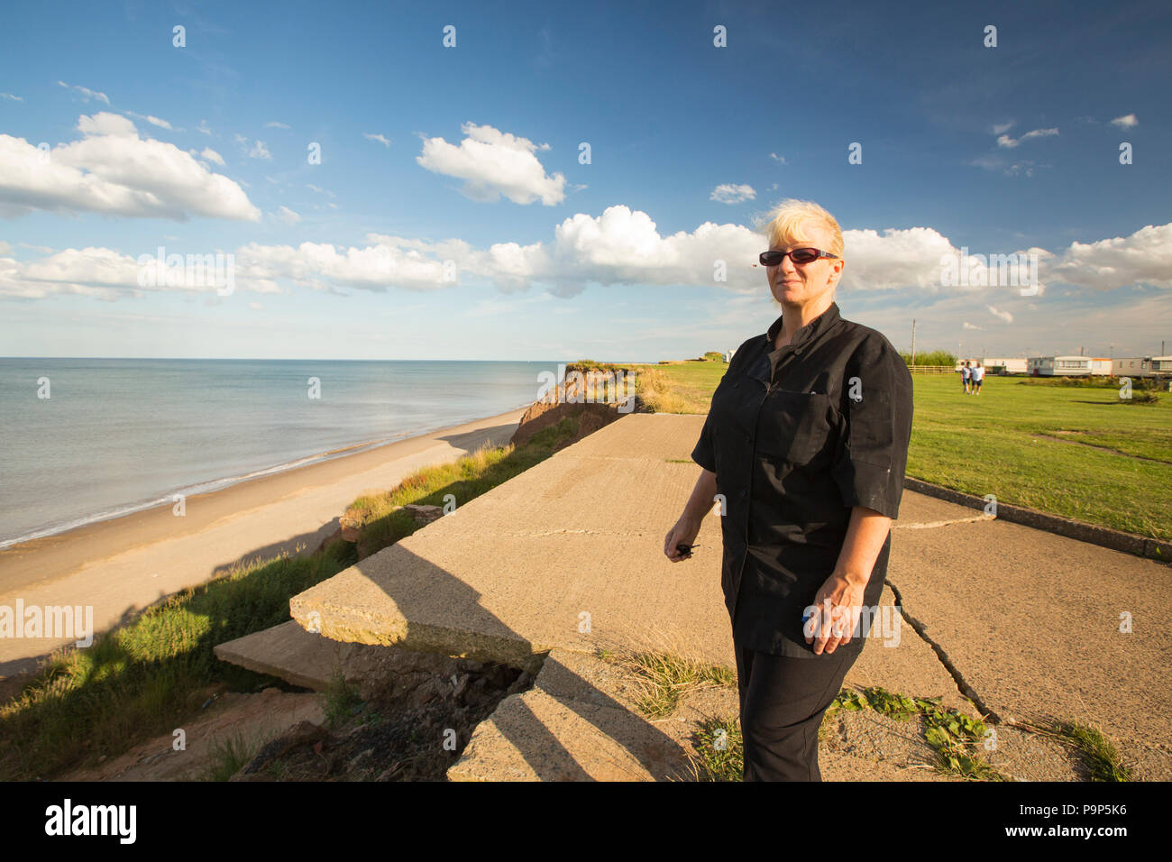 La donna si innalza accanto al bordo del collasso Rupi costiere a Aldbrough Yorkshires sulla costa est, UK. Ella si fermò nella posizione in cui il suo uso interno Foto Stock