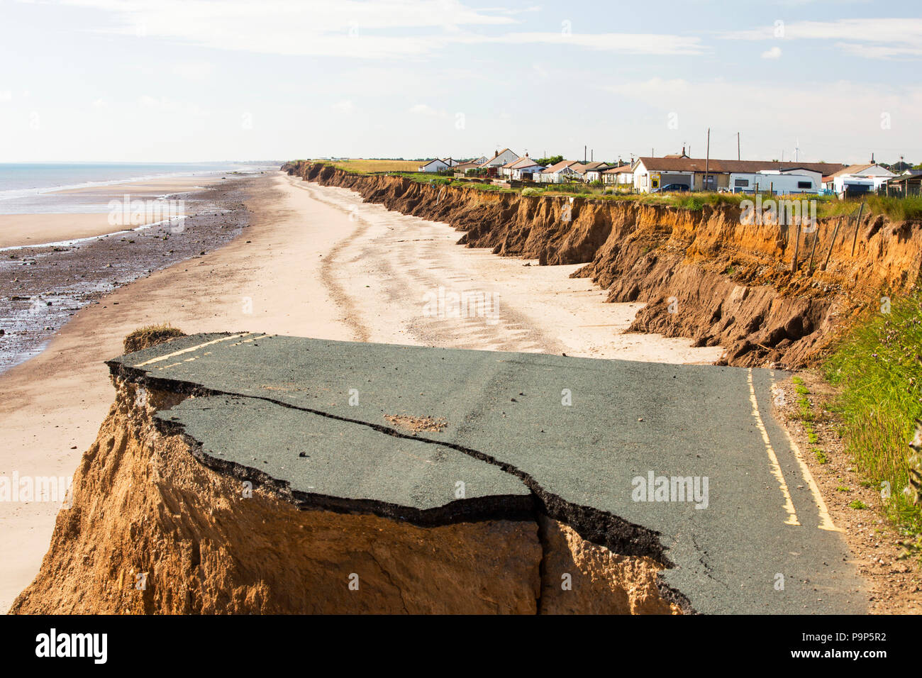 È crollata una strada costiera tra Skipsea e Ulrome Yorkshires sulla costa est, vicino Skipsea, UK. La costa è composta da morbide argille di boulder, molto vulnerabili alla erosione costiera. Questo tratto di costa è stata erodendo sin dai tempi dei romani, con molti villaggi aventi scompare in mare, ed è il più veloce erodendo la costa in Europa. Il cambiamento climatico è accelerare l'erosione, con innalzamento del livello del mare, aumentato le tempeste e aumento della pioggia pesante eventi, tutti di fare la loro parte. Foto Stock