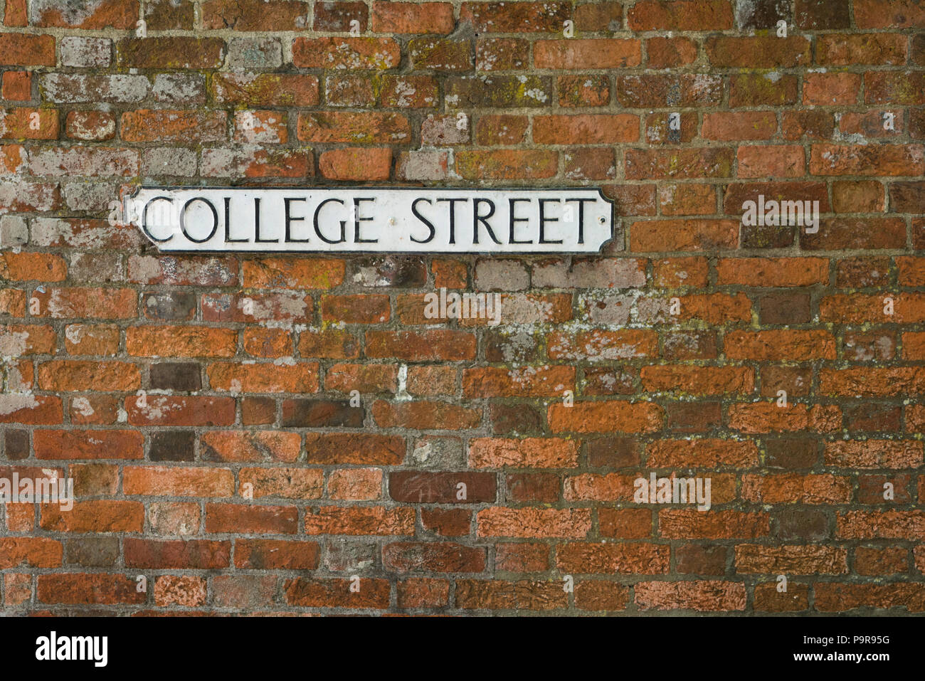 College Street su una strada bianca nome sign impostato su in rosso di un muro di mattoni. Foto Stock