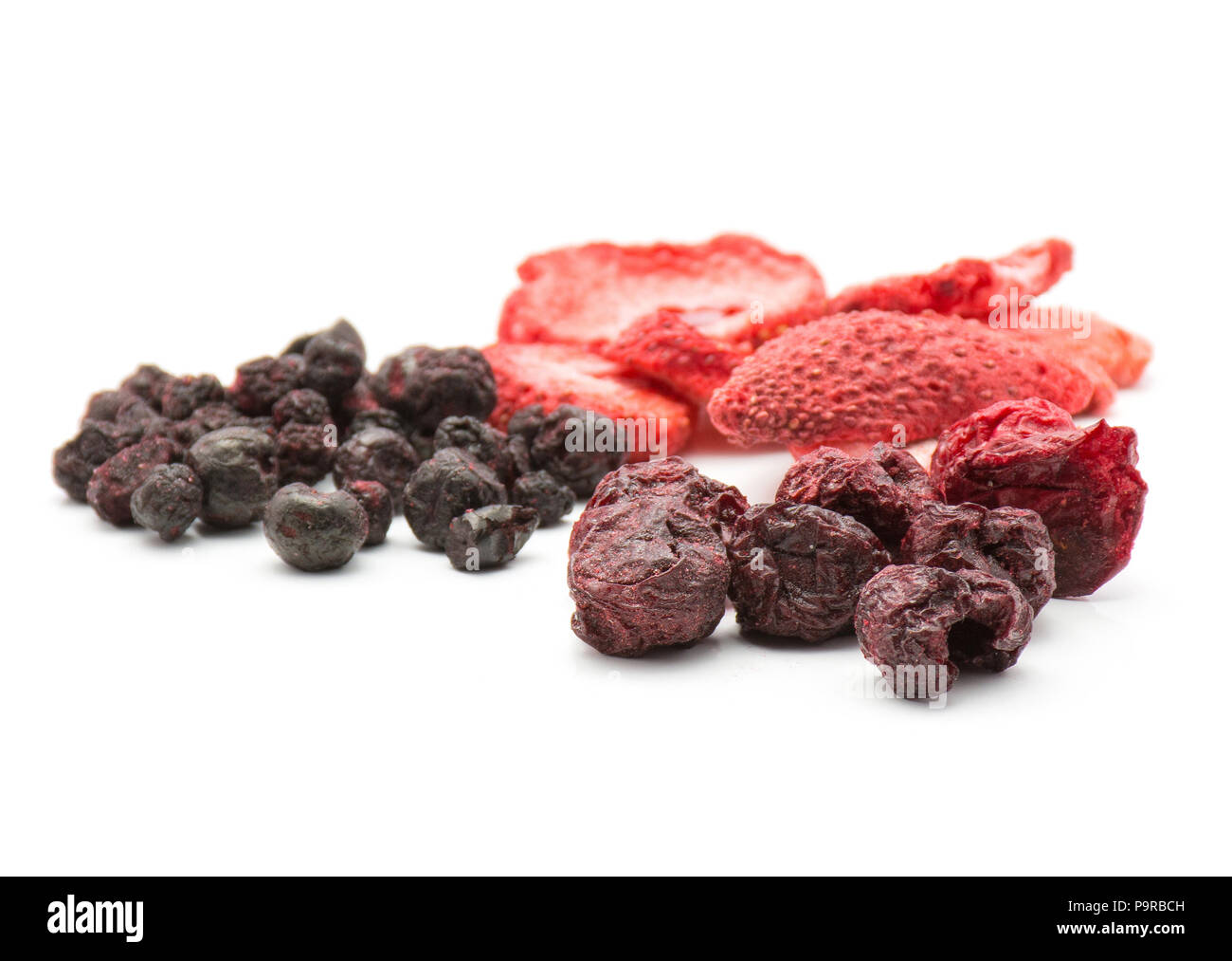 Liofilizzato mix di frutti di bosco isolato su sfondo bianco confrontando fragola mirtillo e ciliegia di pile Foto Stock